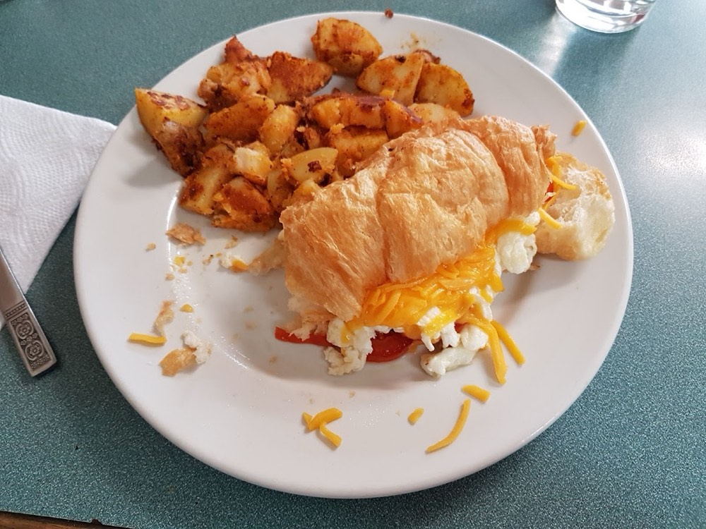 Croissant filled with scrambled egg and melted cheddar, served with panfries