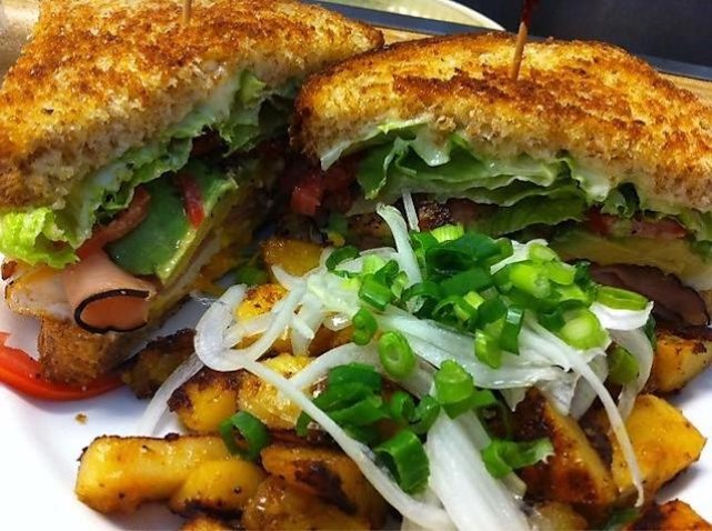 Grilled sandwich with avocado, ham and lettuce, served with panfries and green onion